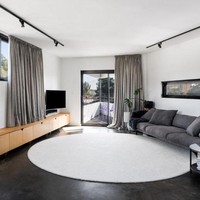 Meskipun dari luar terlihat meragukan karena bentuknya yang meruncing, bagian dalam rumah ternyata cukup luas. Perpaduan warna putih pada dinding dan langit-langit serta abu-abu untuk lantai dan elemen kayu di furnitur memberikan kesan hangat, minimalis dan lega pada ruangan. Foto: Dok. Robeson Architect