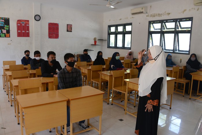 Seorang guru memberikan arahan kepada murid baru dalam ruangan kelas dengan pembatasan jaga jarak saat simulasi penerapan protokol kesehatan di SMA-1 Banda Aceh, Aceh, Sabtu (11/7/2020). Sebagian SMA/SMK di daerah itu menyatakan siap memulai Proses Belajar Mengajar (PBM) tahun ajaran baru 2020/2021 yang dijadwalkan pada, Senin (13/7/2020), baik secara tatap muka maupun daring dengan penerapan prorokol kesehatan guna mencegah penyebaran COVID-19, namun hingga saat ini pihak sekolah masih menunggu keputusan dari pemerintah. ANTARA FOTO/Ampelsa/hp.