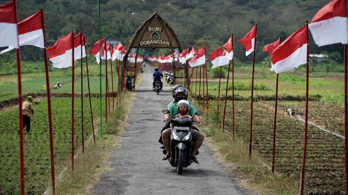 Pengendara sepeda motor melaju di kawasan Dobangsan, Giripeni, Wates, Kulon Progo, D.I Yogyakarta, Rabu (19/8/2020). Jalan kampung yang dihiasi ribuan bendera Merah-Putih untuk memperingati HUT ke-75 Kemerdekaan Republik Indonesia itu menjadi destinasi wisata alternatif di D.I Yogyakarta khususnya bagi para pemburu swafoto. ANTARA FOTO/Andreas Fitri Atmoko/aww.