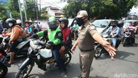 Petugas menghentikan pengendara yang tidak memakai masker.