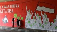 Sejumlah anak tampak bermain di depan dinding yang dihiasi dengan mural bertema melawan penyebaran virus Corona.