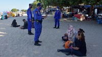 Sejumlah polisi pun melakukan pengawasan dan memberikan teguran kepada para wisatawan yang tak mengenakan masker dan tak menerapkan protokol kesehatan saat berwisata di pantai tersebut. ANTARA FOTO/Nyoman Hendra Wibowo.