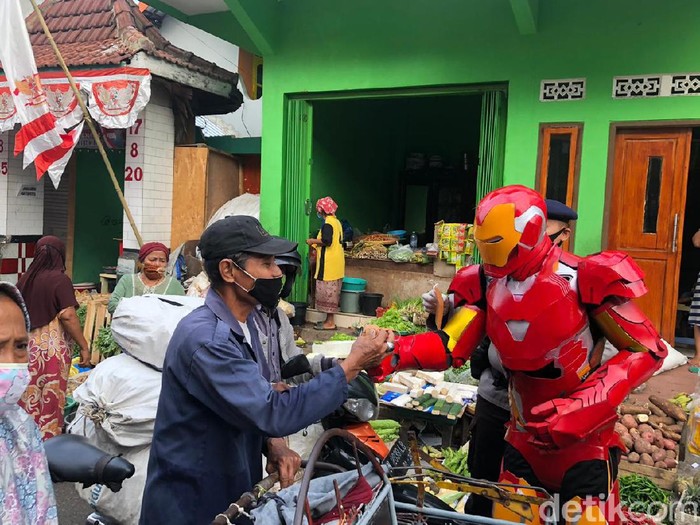 Ada yang beda dari personel Satbrimob Polda Jawa Timur hari ini. Mereka mengenakan kostum superhero saat membagikan masker.