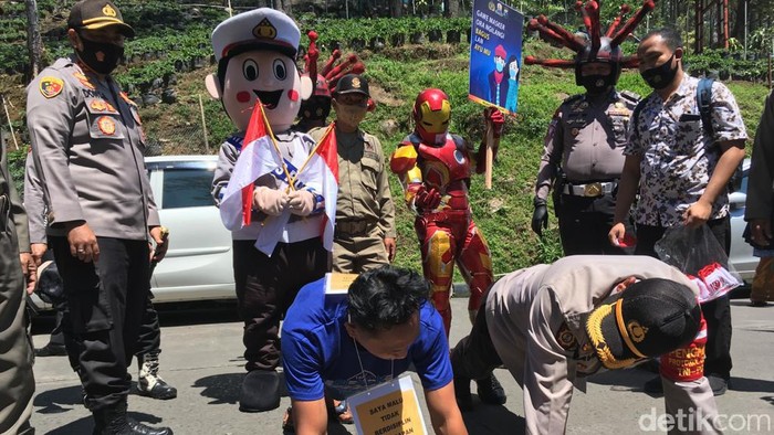 Petugas gabungan menggelar sweeping ke objek wisata di Kabupaten Mojokerto yang ramai pengunjung pada long weekend. Para wisatawan yang kedapatan tidak memakai masker dibuat jera dengan disanksi menyapu jalan, push up, menghafalkan Pancasila, serta menyanyikan lagu nasional.