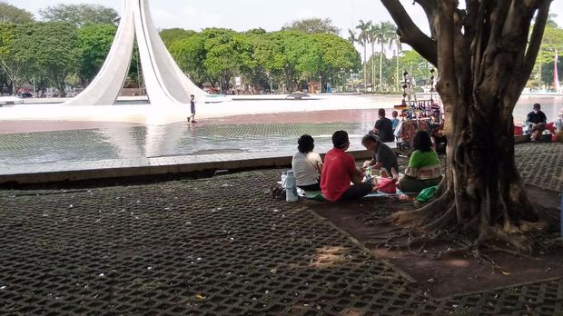 Tampak Warga Duduk Bersama Keluarga di Tugu Api Pancasila TMII