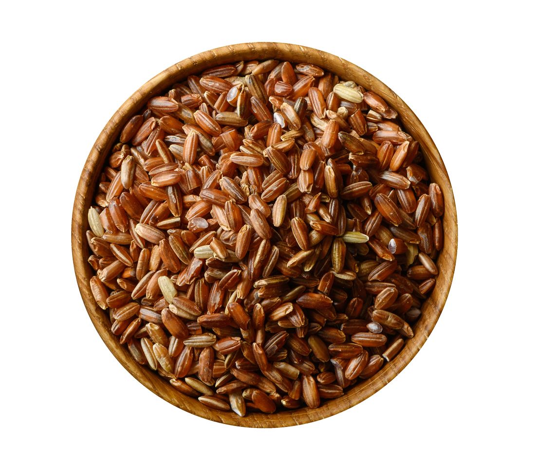 Wooden bowl with uncooked brown rice isolated on white background. Top view
