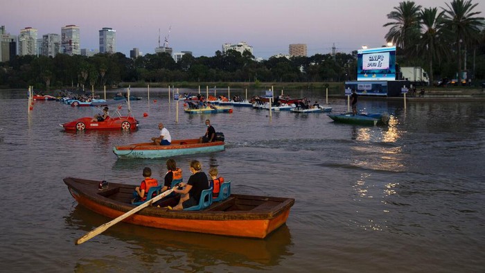 Di Israel Ada Bioskop Apung Lho! People watch a movie at HaYarkon Park's boating lake in Tel Aviv, Israel, Thursday, Aug. 20, 2020. As movie theaters in Israel remain shut because of the coronavirus outbreak, Tel Aviv Municipality launch a