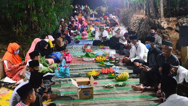 Warga memanjatkan doa bersama saat menggelar tradisi Barikan di Dusun Pliringan, Dawe, Kudus, Jawa Tengah, Kamis (20/8/2020). Tradisi untuk menyambut tahun baru islam 1442 H dengan menggelar doa bersama kemudian dilanjutkan saling bertukar makanan seperti nasi dan lauk pauk, ingkung, buah-buahan hingga camilan itu sebagai wujud syukur kepada Tuhan Yang Maha Esa serta untuk mempererat kerukunan antar warga. ANTARA FOTO/Yusuf Nugroho/pras.