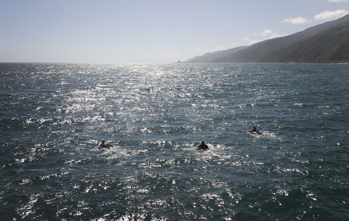 A group of bricklayers by trade float on their inner tubes in fishing in the open sea to fish at Playa Escondida in La Guaira, Venezuela, Friday, Aug. 14, 2020. Venezuelans desperate to feed their families amid the coronavirus pandemic are heading out to the open sea on inner tubes armed with a hook and line. It’s a risk they’re forced to take as the nationwide lockdown paralyzes an already failing economy and eliminates their jobs in construction and restaurants.  (AP Photo/Matias Delacroix)