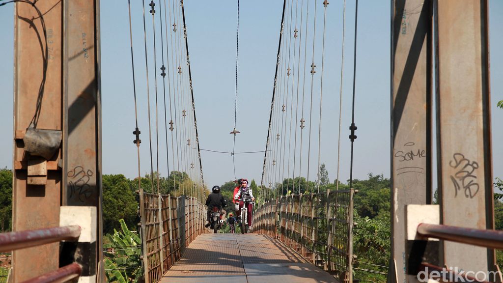 Warga melintas di jembatan gantung di Curug, Depok, Jabar. Jembatan yang membentang di atas Kali Angke tersebut menghubungkan Depok dengan Bogor.