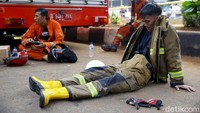 Petugas pemadam kebakaran beristirahat di jalanan setelah berhasil memadamkan api. 