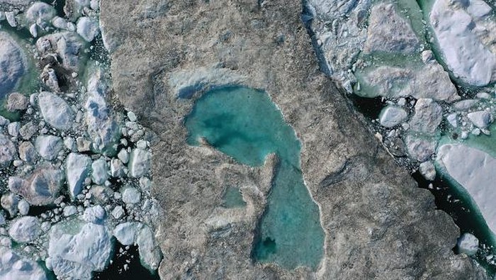 ILULISSAT, GREENLAND - JULY 30: An iceberg floats in Disko Bay behind houses during unseasonably warm weather on July 30, 2019 in Ilulissat, Greenland. The Sahara heat wave that recently sent temperatures to record levels in parts of Europe is arriving in Greenland. Climate change is having a profound effect in Greenland, where over the last several decades summers have become longer and the rate that glaciers and the Greenland ice cap are retreating has accelerated.   (Photo by Sean Gallup/Getty Images)
