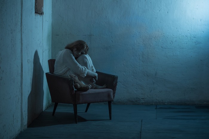 penculikan girl in white dress on old armchair in basement