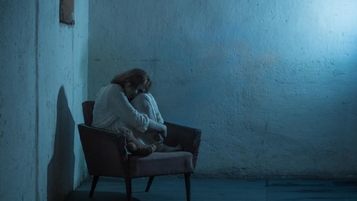 girl in white dress on old armchair  in basement
