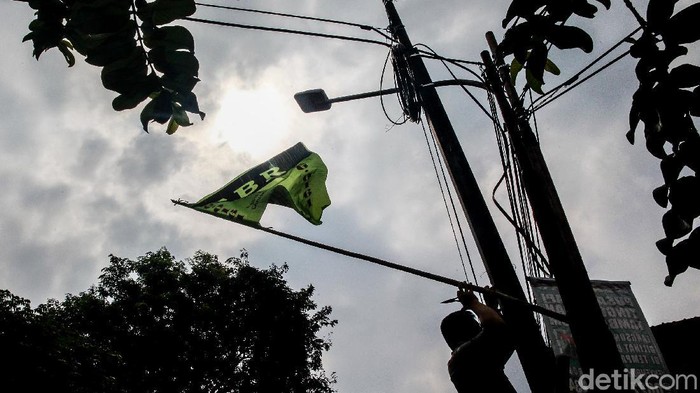 Petugas Satpol PP Kecamatan Pesanggrahan melakukan penertiban atribut ormas di Jl Bintaro Permai Raya, Jakarta Selatan, Senin (24/8/2020). Penertiban dilakukan untuk menjaga keindahan kota dan kenyamanan warga. Atribut ormas seperti bendera dan spanduk yang kerap ditemui terpasang di tiang kabel. utilitas jalan, pepohonan atau pagar pekarangan yang berada di sisi jalan raya.