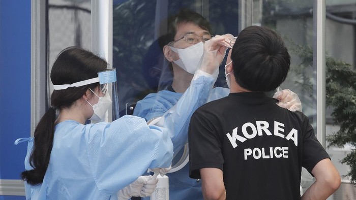 A medical worker takes samples from a police officer during COVID-19 testing at the Seoul Metropolitan Police Agency in Seoul, South Korea, Wednesday, Aug. 19, 2020. (AP Photo/Ahn Young-joon)