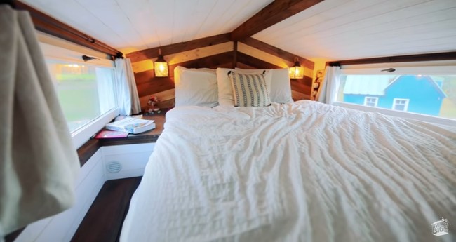 Siapa sangka jika rumah mungil ini memiliki lantai dua. Pada lantai dua, ada tempat tidur nyaman yang menjadi tempat Jonathan dan Yunae beristirahat. Jendela di sisi kiri dan kanan menjadi pelengkap ruangan yang membuat mereka betah berada di kamar. Dengan jendela tersebut sinar matahari bisa masuk dengan mudah dan jika hujan tiba mereka bisa tetap menikmati keindahan alam di luar sambil berbaring di tempat tidur. Foto: Youtube Living Big In A Tiny House