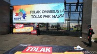 Sejumlah buruh memasang spanduk menolak RUU Cipta kerja di pagar gedung DPR, Selasa (25/8).