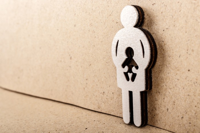 Mother and child. Wooden figure on brown paper background. Pregnancy, abortion or adoption concept.