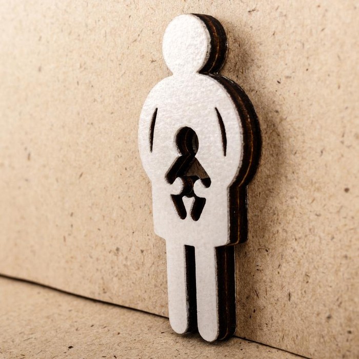 Mother and child. Wooden figure on brown paper background. Pregnancy, abortion or adoption concept.