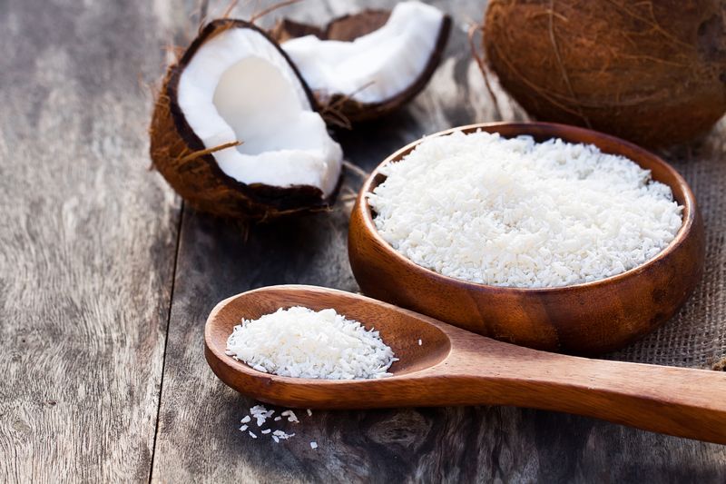 Cracked  coconut and flakes on rustic wooden table background