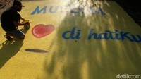 Seorang pelukis tampak menyelesaikan hiasan di jalan dengan mural 3 dimensi.