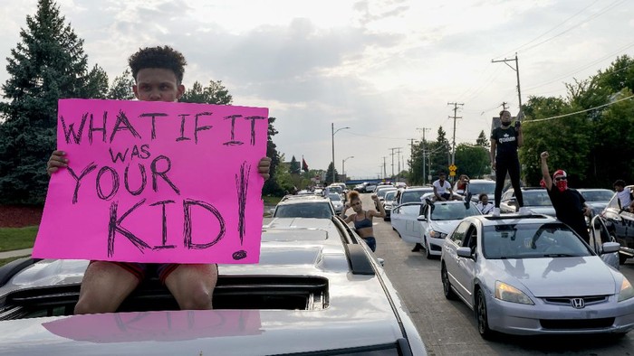A protester sits on a car as they stop traffic Monday, Aug. 24, 2020, in Kenosha, Wis. Wisconsin Gov. Tony Evers has summoned the National Guard to head off another round of violent protests after the police shooting of a Black man turned Kenosha into the nations latest flashpoint city in a summer of racial unrest. (AP Photo/Morry Gash)
