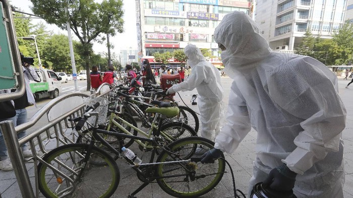 Workers and volunteers disinfect as a precaution against the coronavirus on a street in Goyang, South Korea, Tuesday, Aug. 25, 2020. South Korea is closing schools and switching back to remote learning in the greater capital area as the country counted its 12th straight day of triple-digit daily increases in coronavirus cases. (AP Photo/Ahn Young-joon)
