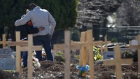 Sepasang suami istri berpelukan di pemakaman khusus COVID-19 di Buenos Aires.