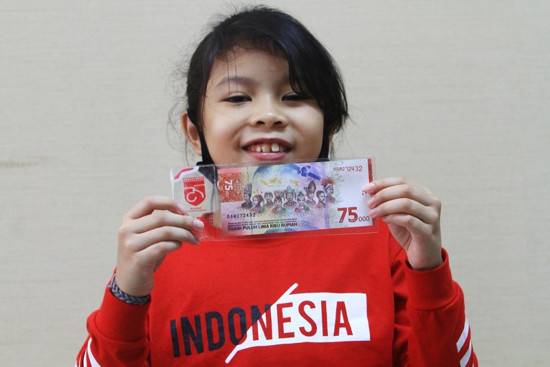 Model desain uang peringatan kemerdekaan 75 Tahun Republik Indonesia, Kalila Aylakiva memperlihatkan selembar uang Rp75 ribu saat jumpa pers di Bank Indonesia Kantor Perwakilan Kalbar di Pontianak, Kalimantan Barat, Selasa (25/8/2020). Kalila Aylakiva (10 tahun) yang merupakan siswa SD asal Pontianak tersebut terpilih untuk menjadi salah satu model dengan mengenakan baju adat Dayak Kantu asal Kalbar yang masuk dalam desain uang pecahan kemerdekaan Rp75 ribu yang diterbitkan Bank Indonesia. ANTARA FOTO/Jessica Helena Wuysang/foc.