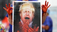 Salah satu demonstran tampak membawa poster bergambar Perdana Menteri Inggris Boris Johnson saat menggelar aksi unjuk rasa terkait tuntutan kenaikan gaji di kawasan London.