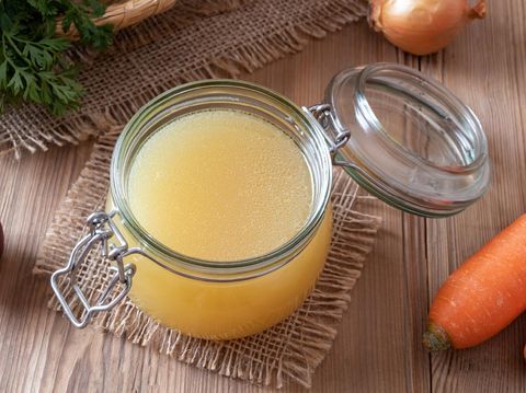 Chicken bone broth in a glass jar and fresh vegetables