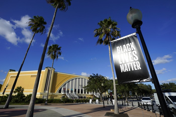 A Black Lives Matter banner hangs outside of the arena after a postponed NBA basketball first round playoff game between the Milwaukee Bucks and the Orlando Magic, Wednesday, Aug. 26, 2020, in Lake Buena Vista, Fla. The game was postponed after the Milwaukee Bucks didn't take the floor in protest against racial injustice and the shooting of Jacob Blake, a Black man, by police in Kenosha, Wisconsin. (AP Photo/Ashley Landis, Pool)
