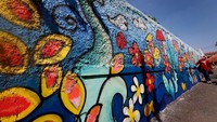 Seniman mural dari komunitas GSSI Bandung Ibey berpose di depan mural karyanya berjudul Warna Warni Kebahagiaan di Bandung, Jawa Barat, Kamis (27/8/2020). Foto: dok. AkzoNobel