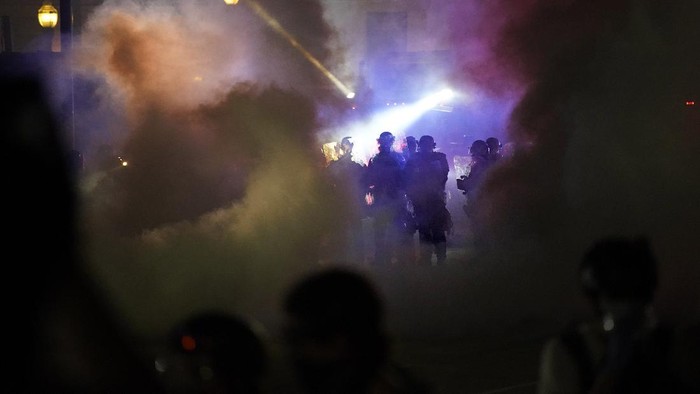 Police in riot gear clear the area in front of Kenosha County Courthouse during clashes with protesters late Tuesday, Aug. 25, 2020, in Kenosha, Wis. Protests continue following the police shooting of Jacob Blake two days earlier. (AP Photo/David Goldman)