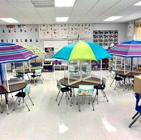 Dengan ruang kelas seperti ini para murid akan merasa lebih terlindungi karena ada kaca akrilik yang membatasi antara satu dengan yang lain, serta payung dengan warna-warna yang cantik dan menarik. Foto: Facebook/Lacy Jenkins