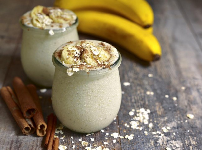 Banana smoothie with oats in a vintage glass jar on a rustic wooden table.