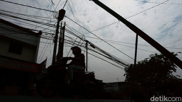 Tiang listrik bengkok dan nyaris roboh terlihat di kawasan Jalan Pergelaran Setu, Cipayung, Jakarta Timur. Hal itu tentu saja dapat membahayakan para pengguna jalan.