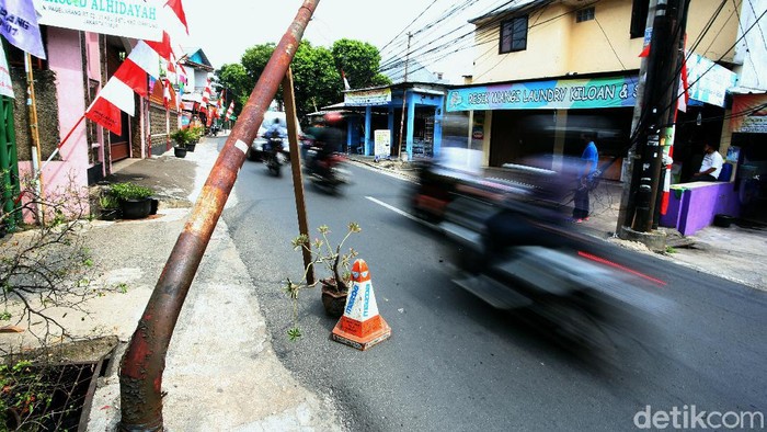 Tiang listrik bengkok dan nyaris roboh terlihat di kawasan Jalan Pergelaran Setu, Cipayung, Jakarta Timur. Hal itu tentu saja dapat membahayakan para pengguna jalan.