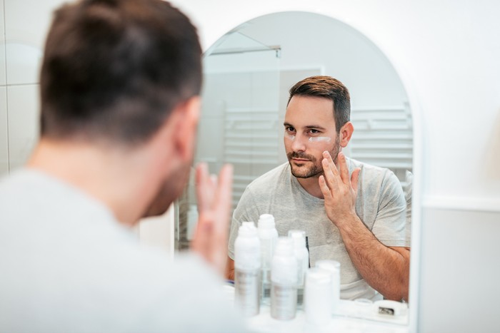 Perawatan wajah pria Handsome man applying face cream in the bathroom.