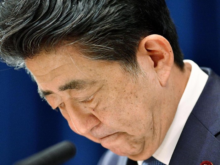 Japanese Prime Minister Shinzo Abe downs his head as he says he is stepping down during a press conference at the prime minister official residence in Tokyo Friday, Aug. 28, 2020. Japans longest-serving prime minister Abe said Friday he intends to step down because a chronic health problem has resurfaced. He told reporters that it was “gut wrenching” to leave so many of his goals unfinished. (Kyodo News via AP)