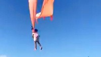 Seorang bocah berusia 3 tahun tersangkut tali layang-layang dan sempat terbawa angin di sela-sela acara festival layang-layang yang tengah diselenggarakan di Hsinchu, Taiwan, Minggu (30/8/2020). Dainese Hsu via AP Photo.