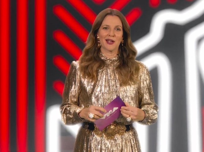 Drew Barrymore bergaya glamor dengan gaun nuansa gold. Belt hitam dengan hiasan emas mempercantik penampilannya yang hadir sebagai pembaca nominasi. Foto: AP/MTV Via AP