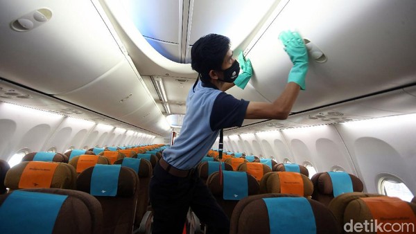 Petugas dengan bermasker melakukan penyemprotan cairan disinfektan pada bagian kabin pesawat Garuda Indonesia di Hanggar GMF AeroAsia Bandara Soekarno Hatta, Tangerang, Banten.