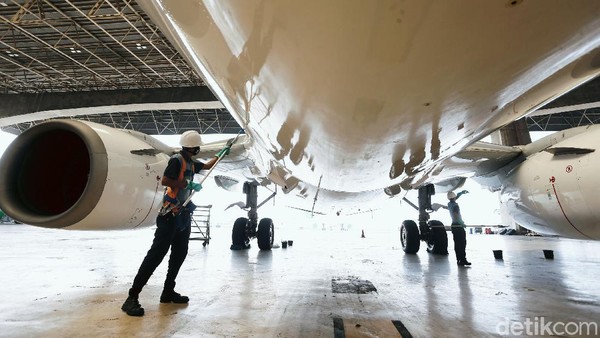 Pekerja Garuda Maintenance Facility (GMF) membersihkan body pesawat bagian luar dan lambung bawah di hanggar Garuda, Cengkareng, Banten.