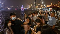 Orang-orang memenuhi sepanjang Sungai Huangpu saat cakrawala kota di distrik Pudong terlihat di Shanghai, China.  