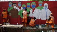 Petugas menyelesaikan pembuatan mural yang berisi pesan waspada penyebaran virus Corona, Senin (31/8/2020).