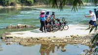 Para pesepeda berfoto dengan latar belakang Sungai Cisadane.