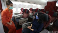 Seorang pramugari bertugas dengan mengenakan masker saat menyapa penumpang yang berada di atas pesawat terbang tersebut.