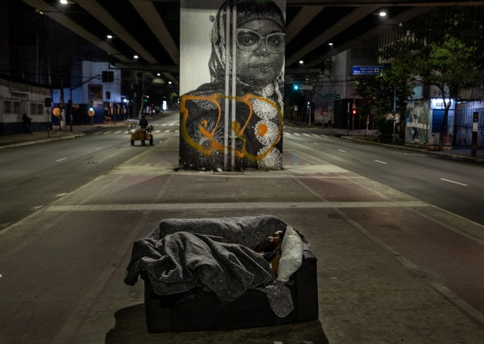 Tunawisma Brasil SAO PAULO, BRAZIL - AUGUST 28: A homeless person sleeps in the sidewalk next to a closed shop at the city centre on August 28, 2020 in Sao Paulo, Brazil. According to an official survey by the Municipality of Sao Paulo, homelessness increased 53% in the capital city over the last five years, reaching a total of more than 25,000 homeless people. Due to the pandemic, unemployment is rising and the number of people living on the streets has increased considerably. The situation worsens during winter with intense cold at night as two deaths have already been recorded. Many of these homeless people prefer staying on the streets rather than going to shelters for fear of contracting coronavirus (COVID-19), and survive only with the help of NGOs and social projects that donate blankets, clothing and food. (Photo by Alexandre Schneider/Getty Images)